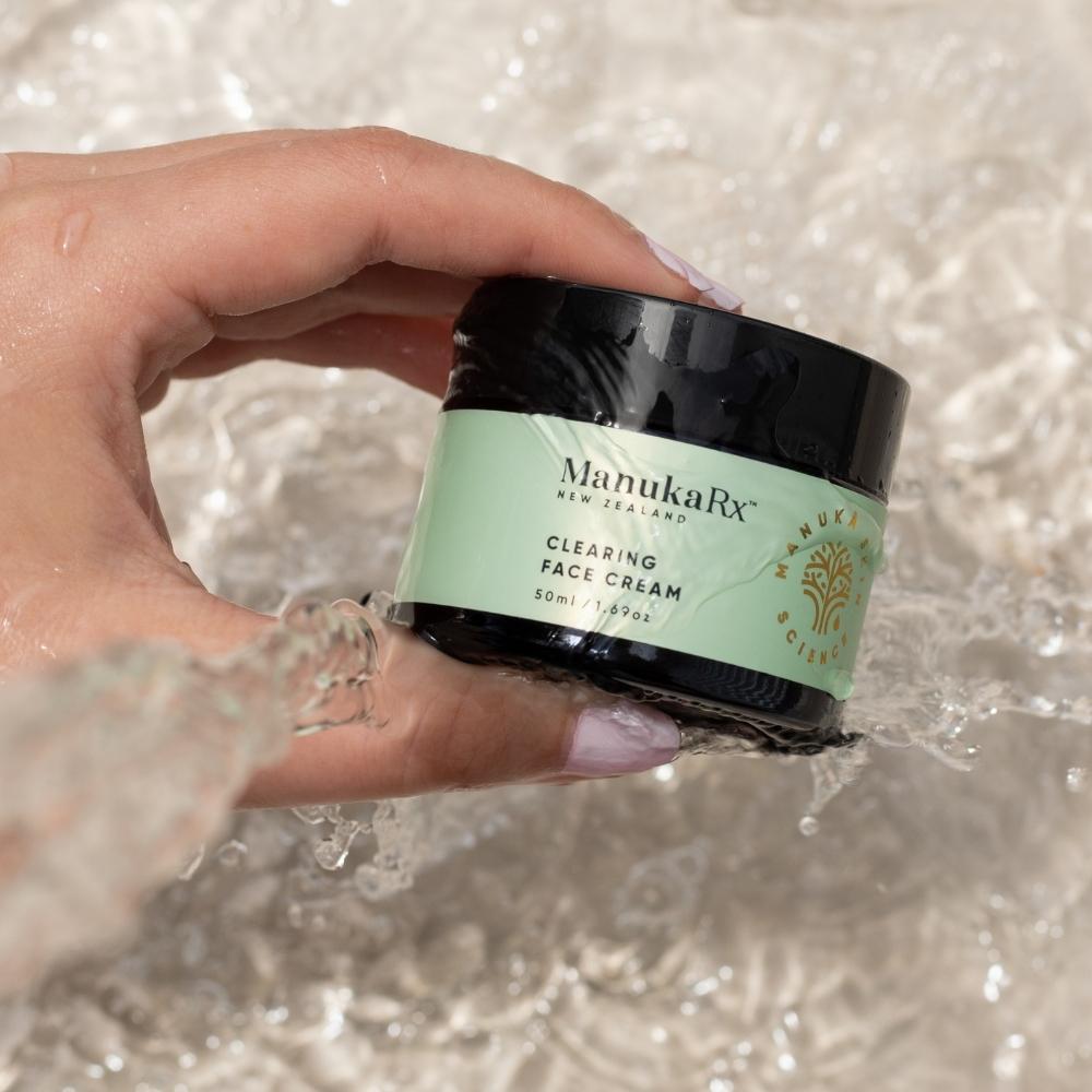 Hand holding ManukaRX Clearing Face Cream in water